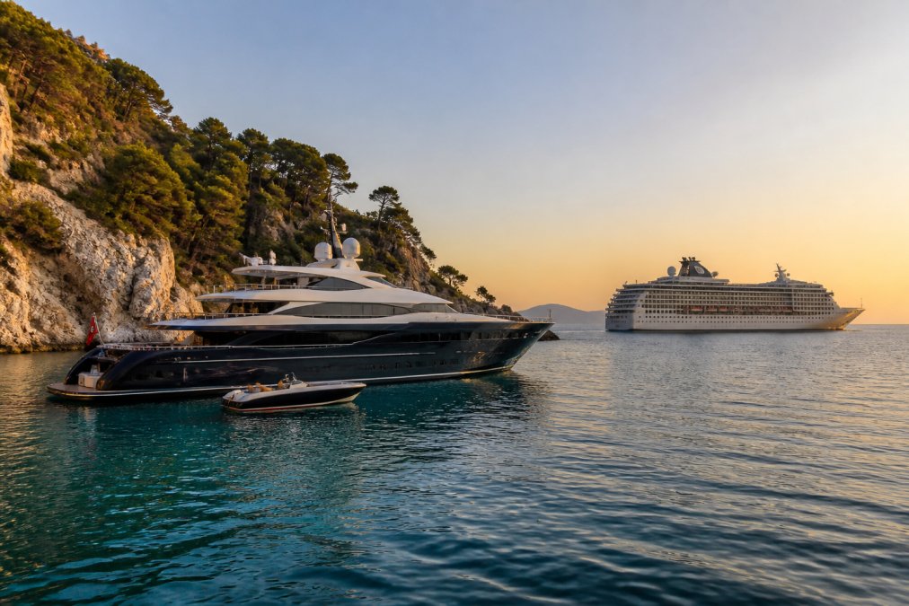 A sleek private yacht charter anchored in a calm Mediterranean cove during a golden hour sunset