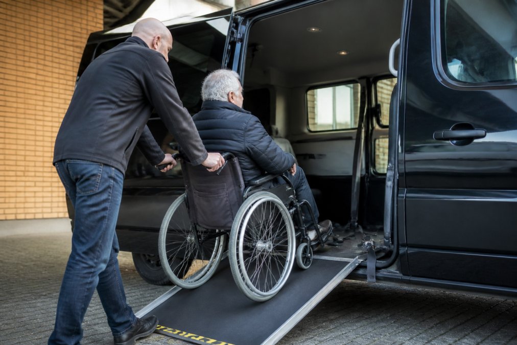 Chauffeur helpt rolstoelgebruiker in aangepast voertuig voor rolstoelvervoer vergoeding 2026