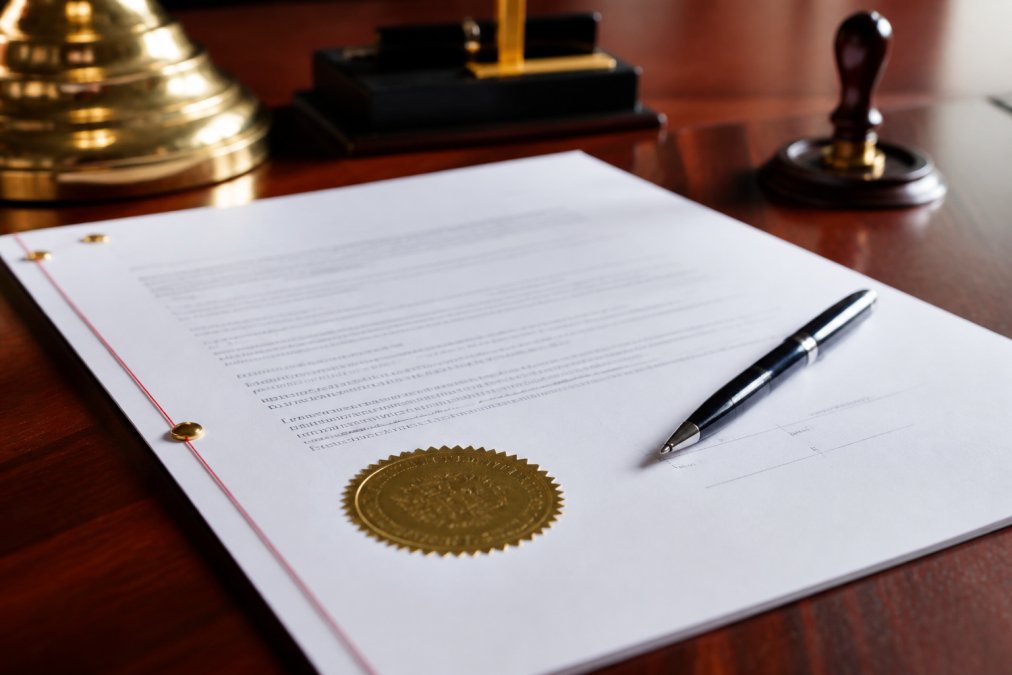 Close-up of a notarized legal document with official seal and pen resting on mahogany desk in professional office setting, representing the legal formality of a Transfer on Death deed