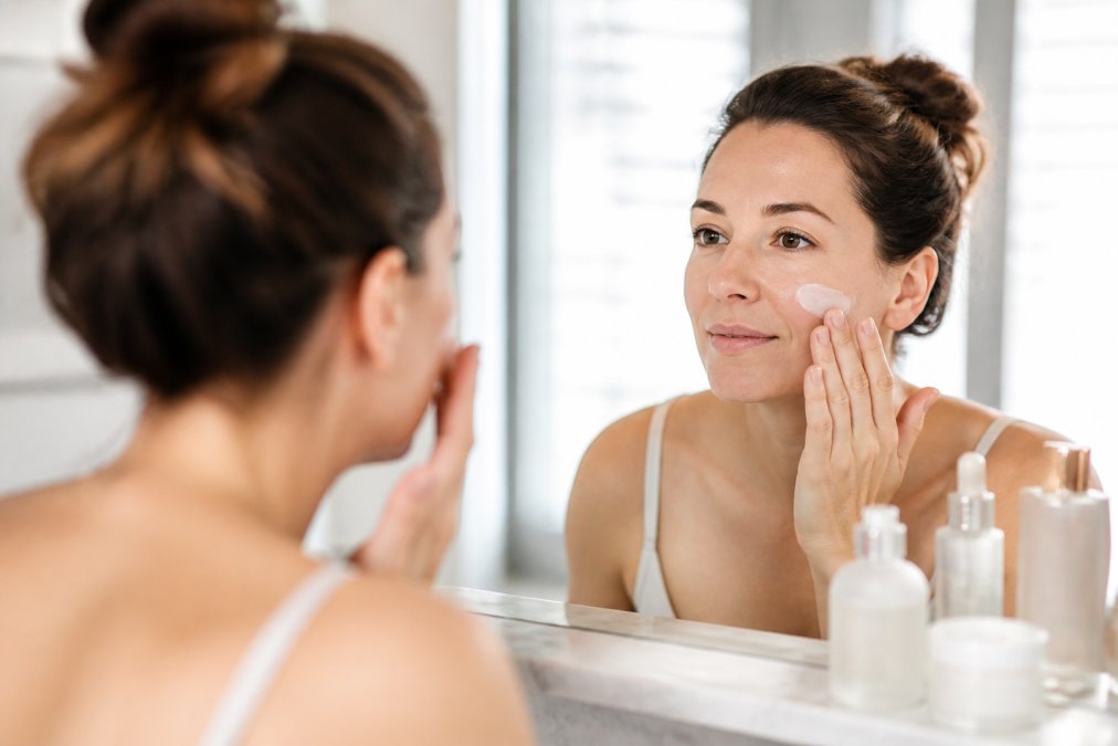 Femme appliquant une crème apaisante sur sa peau parmi nos produits beauté testés