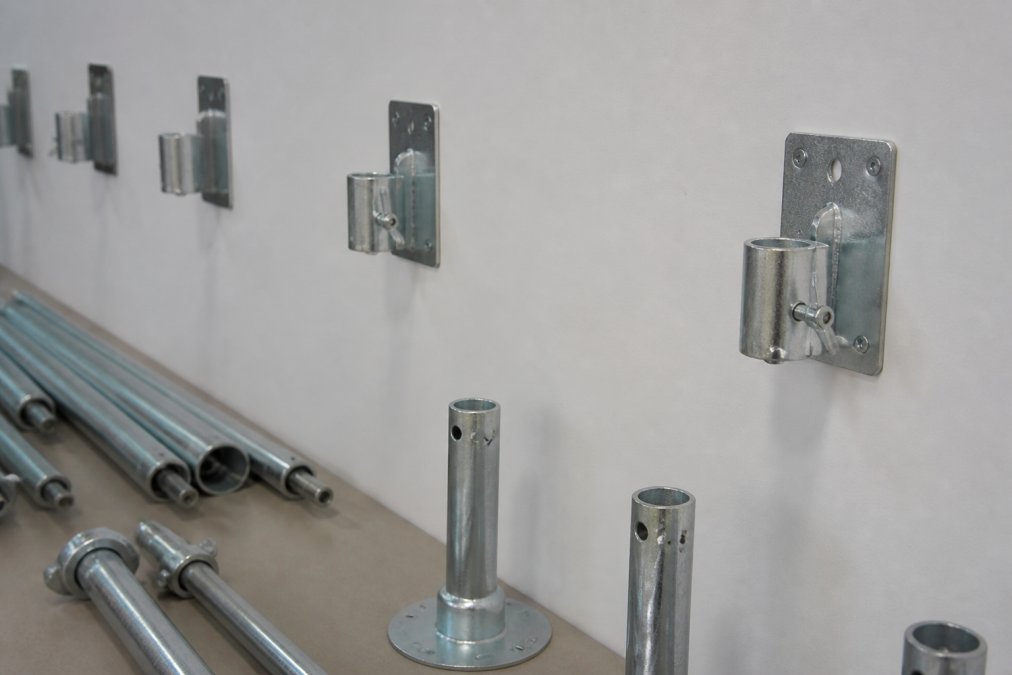 Close-up of mounting hardware, brackets, and traverse rods being prepared for installation on a white wall, showing proper alignment and spacing