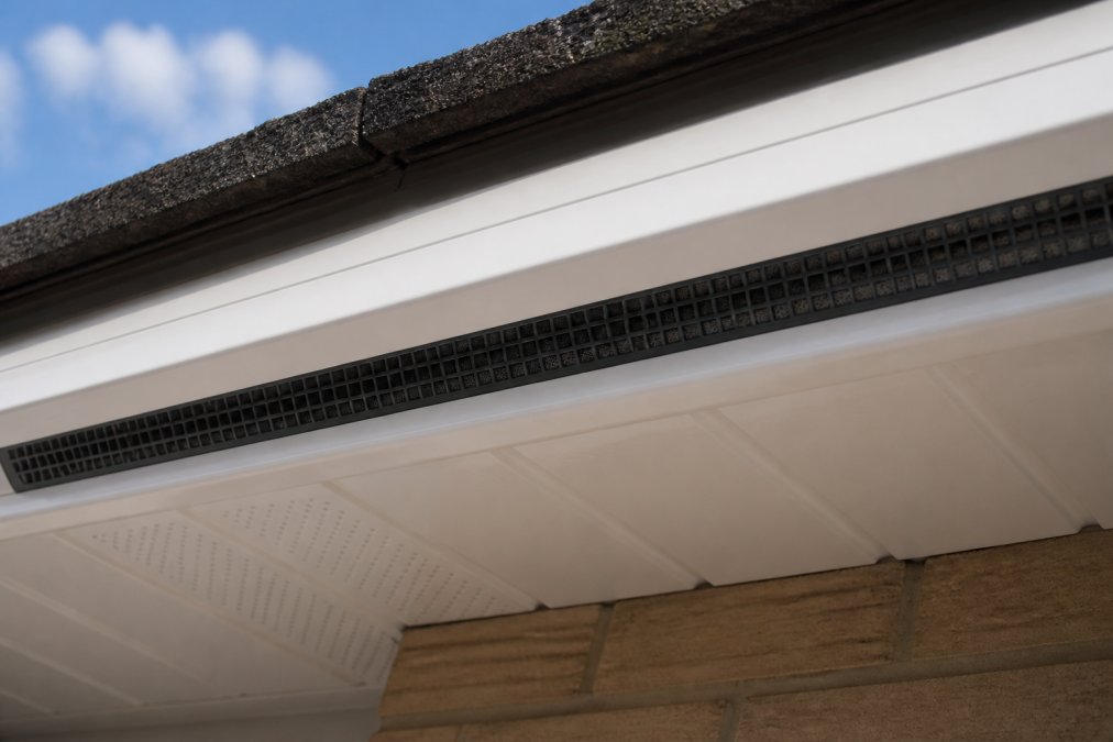 Close-up of soffit vents installed in fascia board, showing ventilation strips and bird comb protection mesh preventing bird entry, with clear airflow path visible