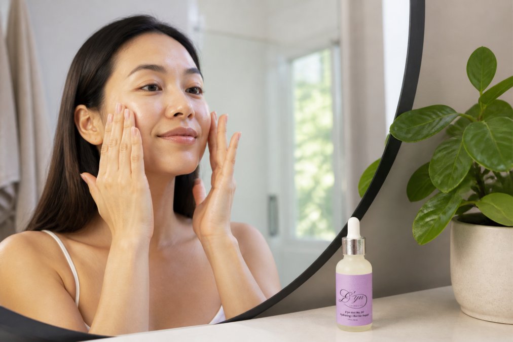 Hands applying serum to face as part of morning skincare routine, showing proper application technique with fingertips gently pressing serum into cheeks and forehead in natural bathroom lighting