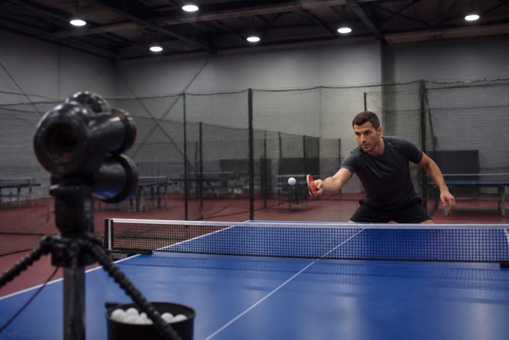 Three-wheel table tennis robot firing balls to a player during professional table tennis training sessions