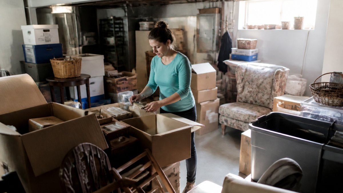Homeowner organizing items in a basement for house clearing vs diy junk, sorting piles for donation and disposal.