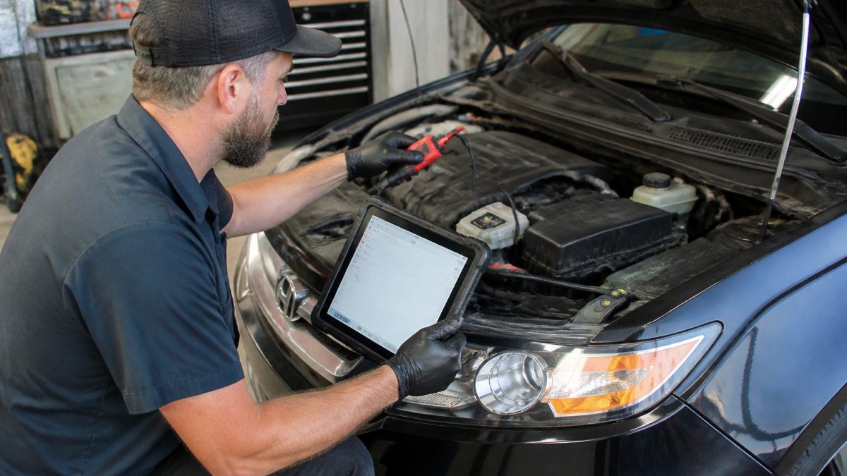 Professional Pre-Purchase Inspection Pricing: 2026 Guide Professional inspector using diagnostic scanner on vehicle engine in well-lit service bay, with tablet displaying fault codes and comprehensive inspection checklist