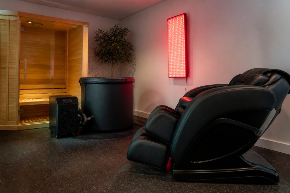 Home recovery room featuring professional recovery equipment like an infrared sauna, cold plunge, and red light therapy.