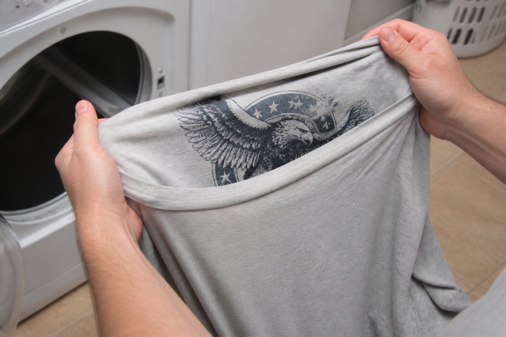 Close-up of hands turning a screen printed t-shirt inside out, showing the printed graphic on the reverse side and the blank interior facing outward