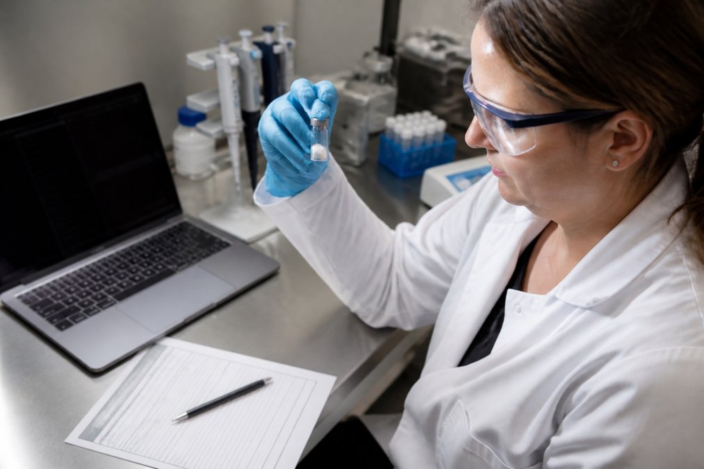 Scientist inspecting a peptide vial and certificate of analysis to compare Protide Health vs Midwest Peptide quality.