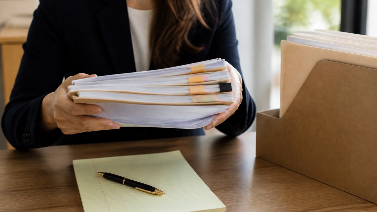 Professional demonstrating organizing medical malpractice evidence with hands holding organized medical records and documents on a table with a notepad and pen in natural lighting
