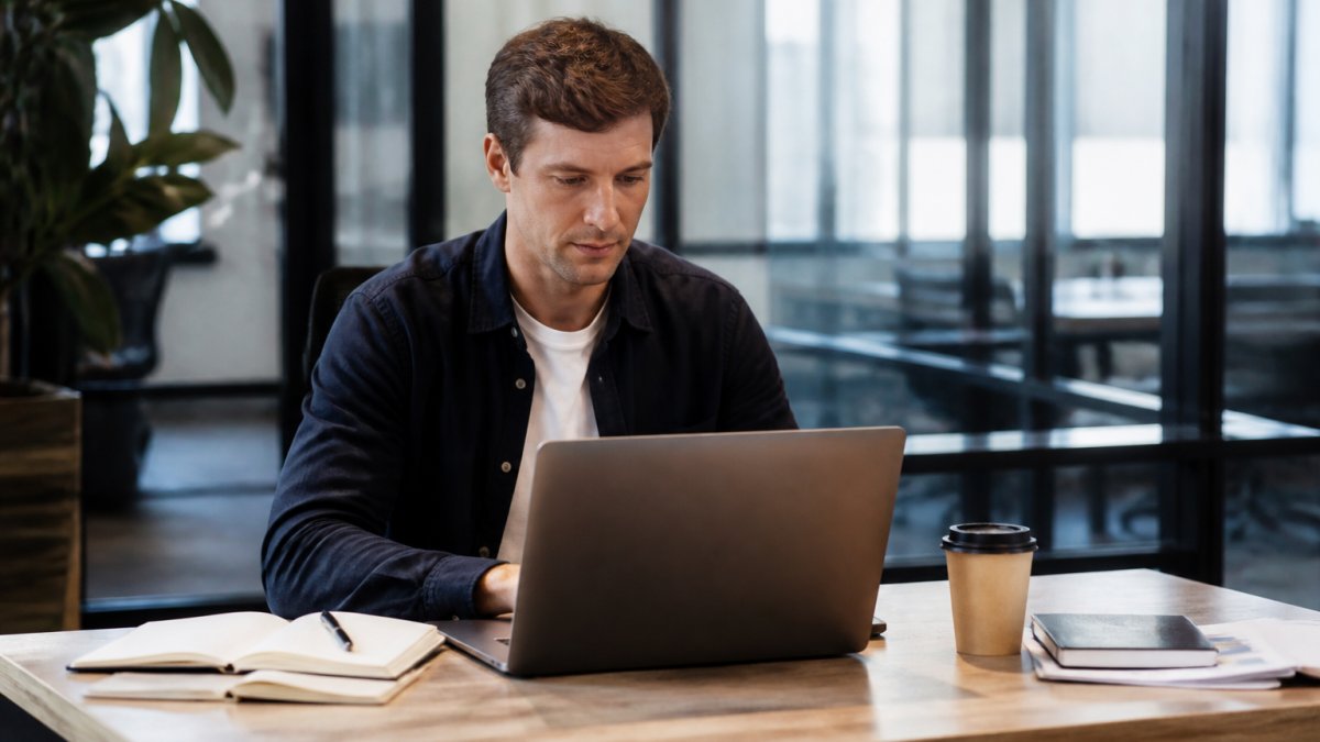 Startup founder reviewing bank connection settings and transaction data on laptop screen in modern office with notebook and coffee nearby
