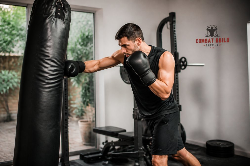 Person in athletic stance performing rapid punching combinations on a heavy bag in a home gym setting, wearing boxing gloves and athletic wear, with proper form and controlled breathing