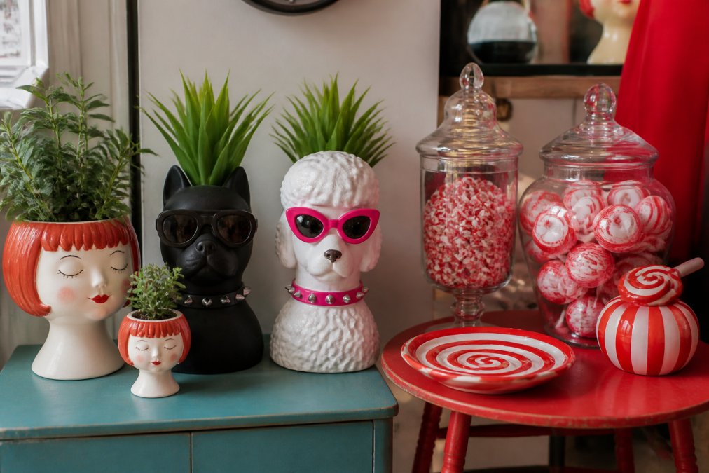 Styled home shelf displaying eclectic quirky décor items including metallic plant pots, statement pieces, and vintage-inspired accessories arranged with natural lighting