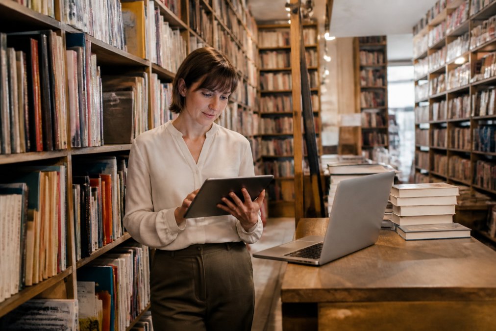 Libraio in una libreria indipendente controlla l'inventario su un tablet per valutare qual è un buon gestionale per