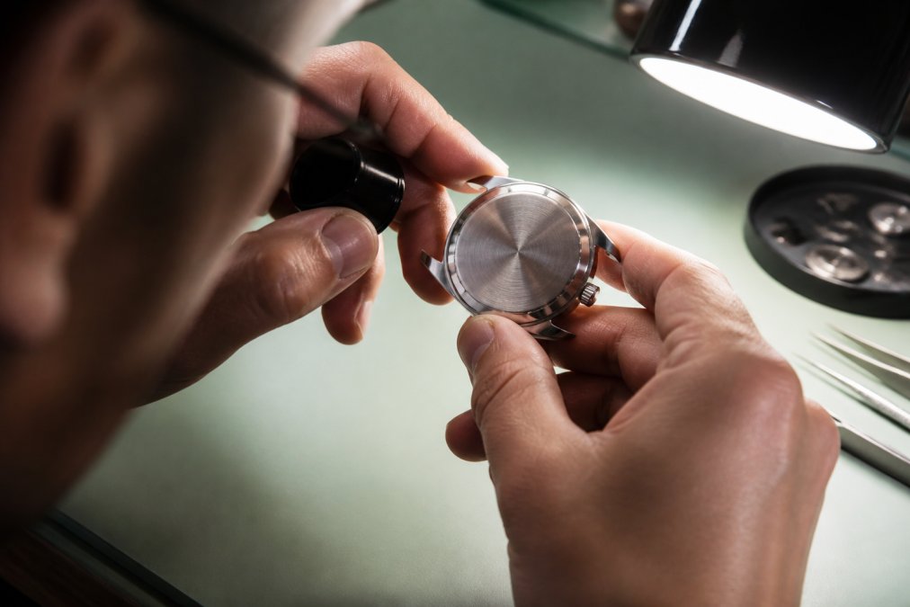 Jeweler examining the depth and clarity of engraved watches using a loupe under bright light