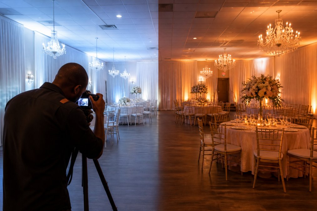 A split view of the same event space, one side lit with cool 5,000 Kelvin light showing a clinical feel, the other side lit with warm 2,700 Kelvin light showing a romantic atmosphere, with a photographer adjusting a camera in the foreground