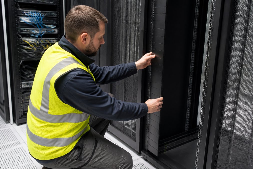 Technician installing a blanking panel to improve rack enclosure airflow in a server cabinet