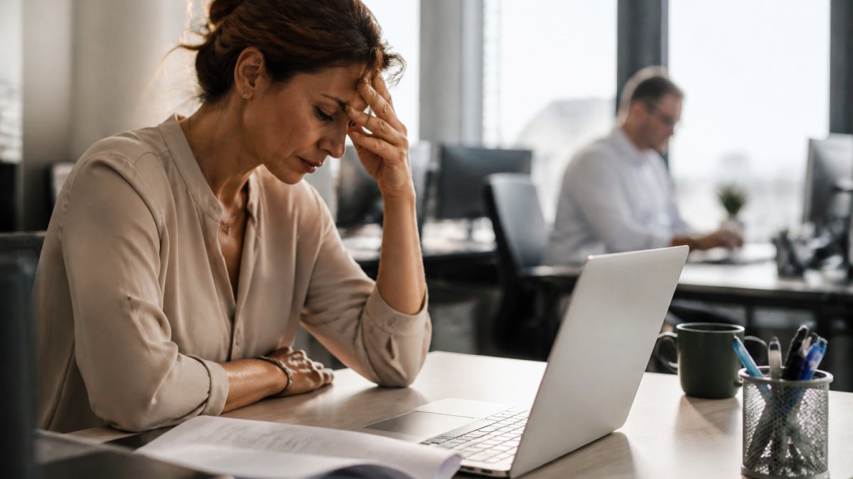 Stressed woman at her office desk feeling the pressure of diet culture while working on a report.
