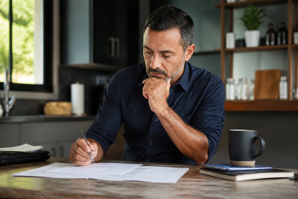 Contractor business owner at laptop reviewing performance analytics and operational reports with coffee, appearing focused and confident while managing growing operations