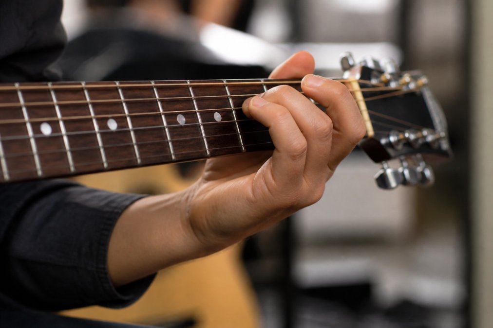 Diagram demonstrating proper finger placement and wrist posture to reduce hand fatigue while playing guitar