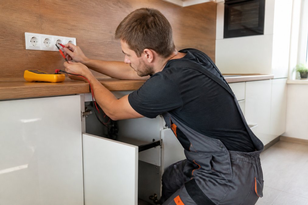 Elektrikář kontroluje elektroinstalaci a&nbsp;zásuvky při realizaci projektu rekonstrukce kuchyně v&nbsp;bytě svépomocí.