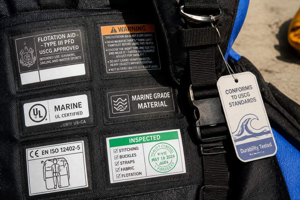 Close-up of safety certification tags and inspection labels on professional water sports equipment showing durability testing stamps and marine-grade material markers