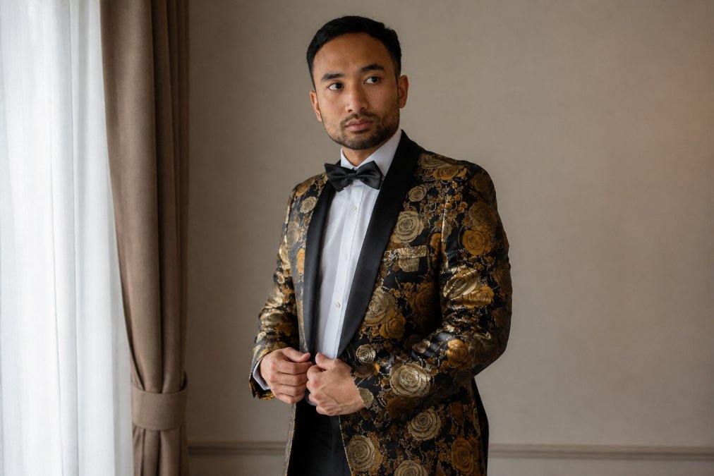 Groom in tailored formal suit standing confidently in natural light, showing proper fit through shoulders and chest with dress shirt and tie