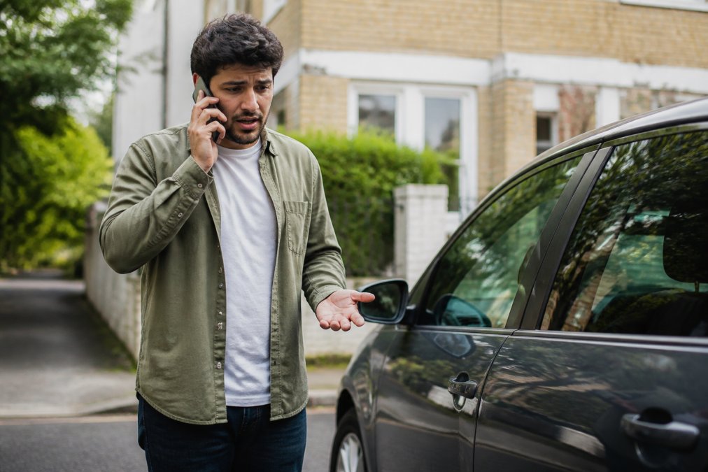 Concerned person using a phone to find help to replace lost car keys cost efficiently while stranded by their vehicle.
