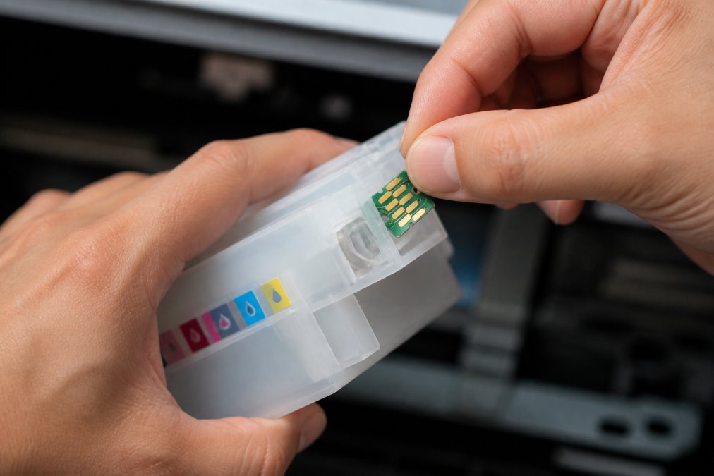 Close-up of hands installing a replacement chip onto an Epson printer cartridge, showing the chip snapping firmly into place on the cartridge connector with proper alignment