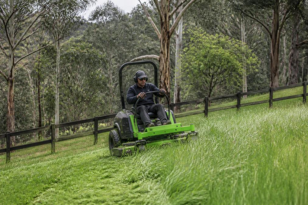 Ride-on mower cutting grass on a sloping acreage block for residential garden maintenance in the Dandenong Ranges