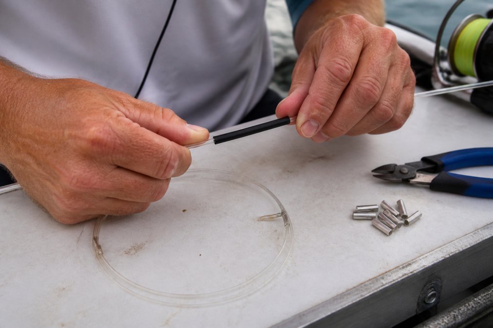 Angler installing protective chafe tubing on a heavy monofilament leader for big game fishing rigs