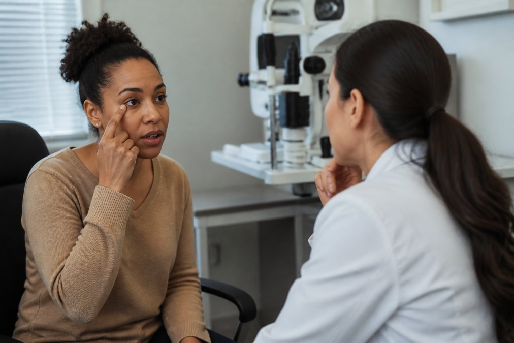 Patient describing vision symptoms to an eye care professional during a consultation, with patient appearing concerned but engaged