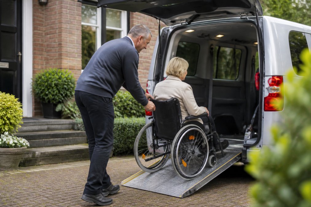 Professionele chauffeur helpt rolstoelgebruiker voorzichtig in een gespecialiseerde rolstoeltaxi met aangepaste ingang en veiligheidssystemen in Utrecht