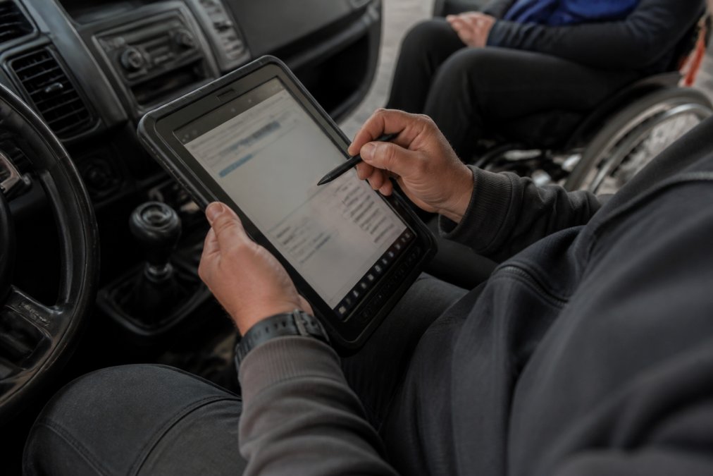 Close-up van tablet met ritprijs berekening waarop chauffeur afstand, tijd en tarief invoert met duidelijk zichtbare kostencalculatie