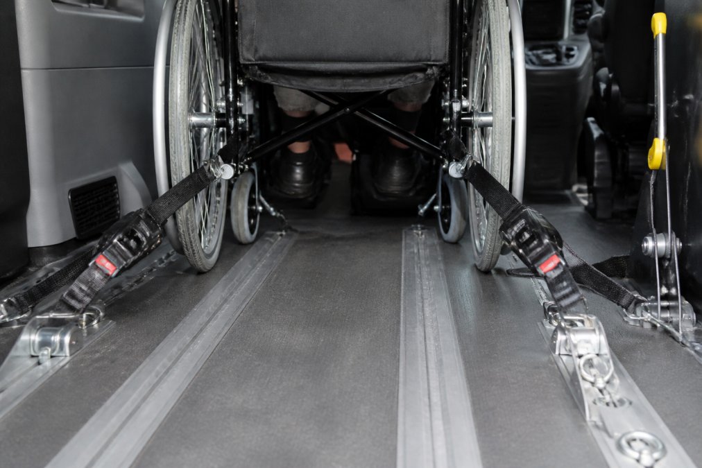 Close-up van een rolstoel die stevig in een aangepaste taxi is vastgezet met professionele bevestigingsbanden en veiligheidssystemen, met zicht op de gecertificeerde beugels en vergrendelingsmechanismen