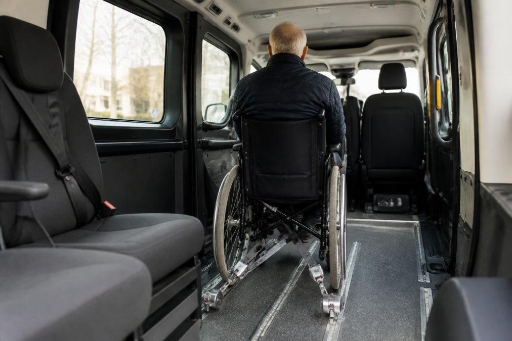 Interieur van een gespecialiseerd rolstoeltoegankelijk voertuig met veilig bevestigde rolstoel, sterke veiligheidsgordels en comfortabele zitplaatsen voor begeleiders in zachte verlichting