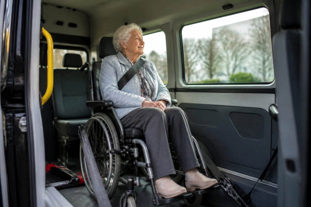 Senior in rolstoel geniet van comfortabel rolstoelvervoer vergelijken tijdens een rit naar een medische afspraak.