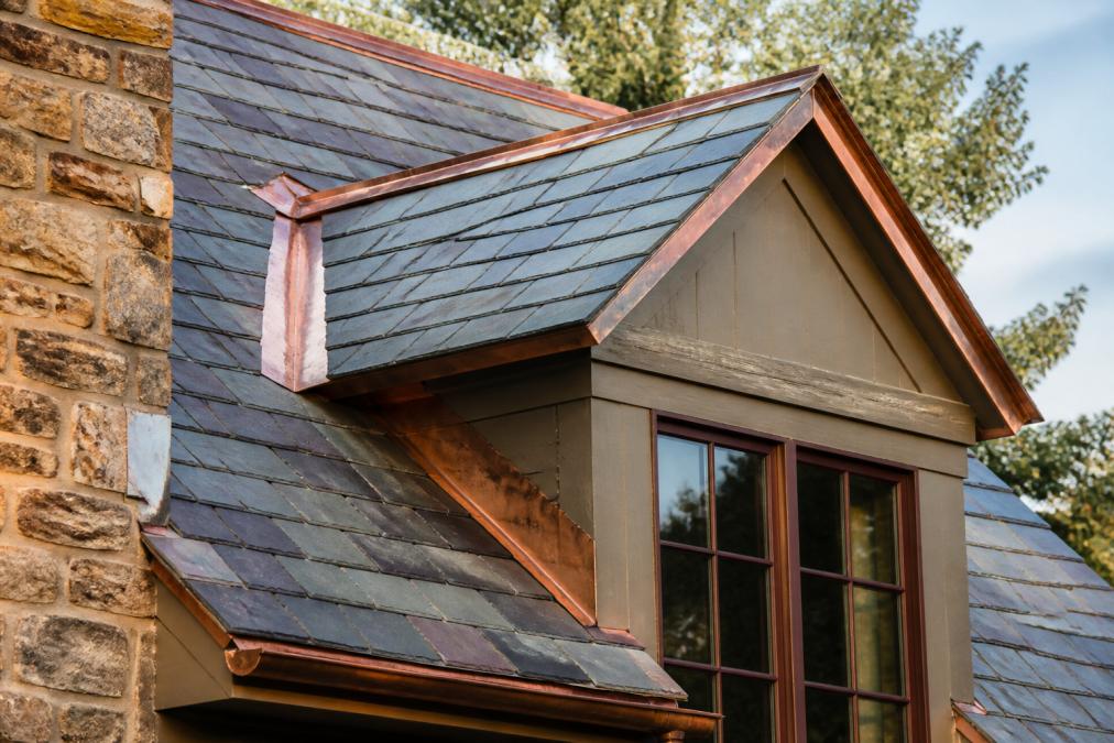 Close-up of a historic home's slate roof with copper flashing, showing natural weathering and craftsmanship under soft afternoon light