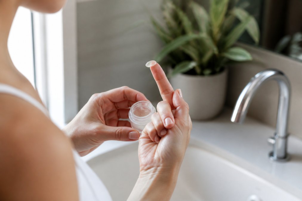 Close-up of a person gently applying a small amount of nasal gel to their fingertip before use, soft natural light in a clean bathroom setting