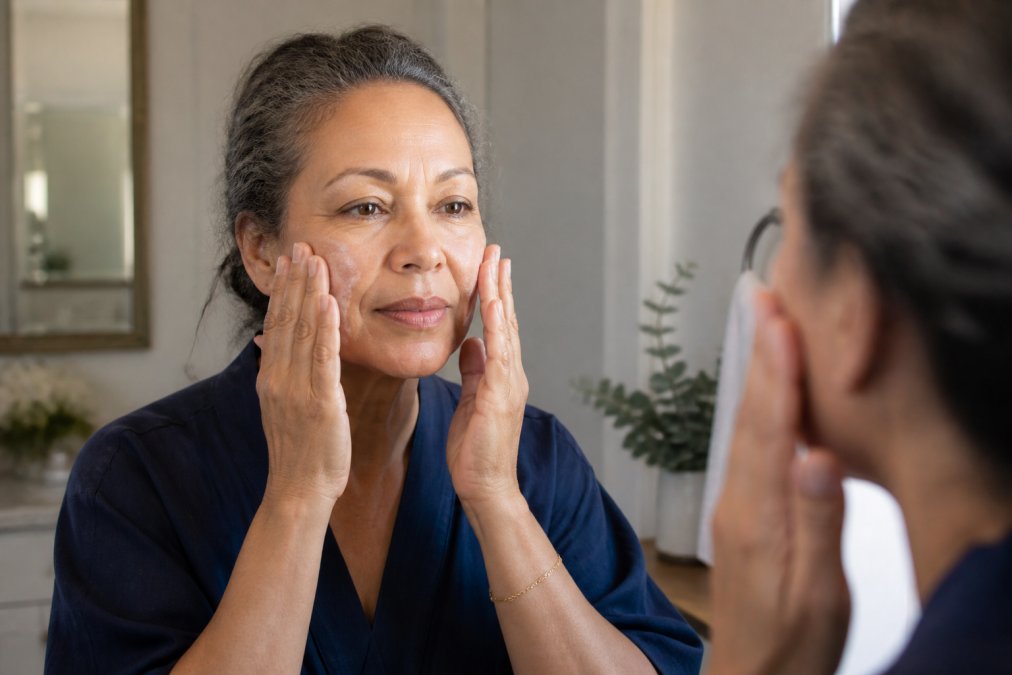 Woman gently pressing cleanser onto her face with fingertips in upward motions, demonstrating minimal-friction application technique on sensitive skin