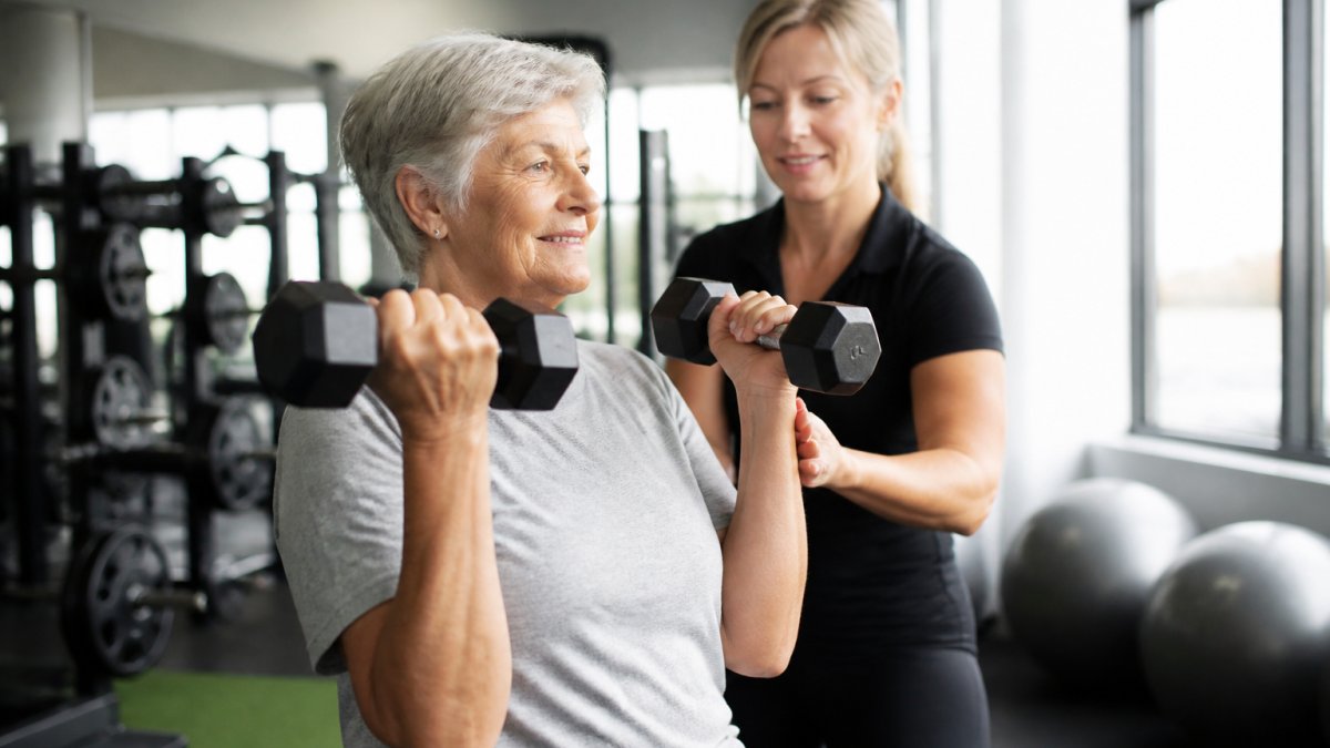 Older adult performing light dumbbell exercises in a clinical setting to support safe weight loss for aging adults