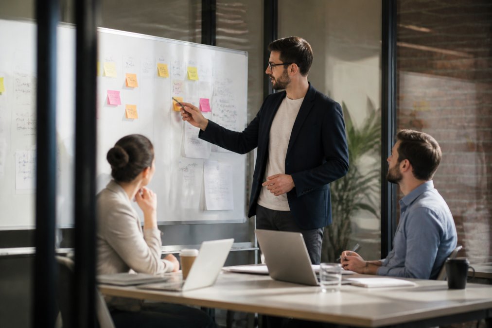 Sales manager explaining pipeline growth strategies to colleagues in a glass-walled meeting room