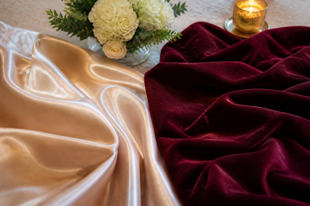 Side-by-side comparison of satin vs velvet fabric textures with floral decor and candle lighting effects