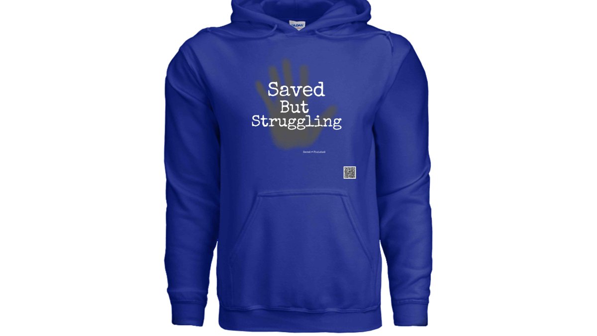 Close-up of the thick cotton fleece fabric of a 'Saved but' hoodie, showing the detailed stitching and ribbed cuffs on a wooden table