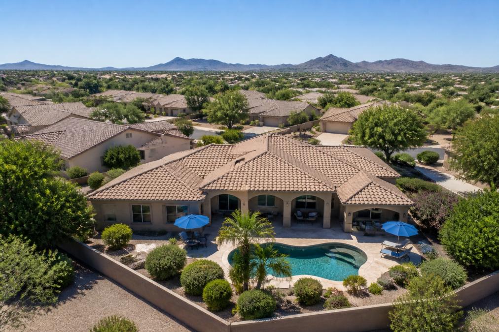 Stunning aerial view of residential property showing complete roofline, mature landscaping, pool area, and surrounding neighborhood context in sharp 4K detail with clear blue sky