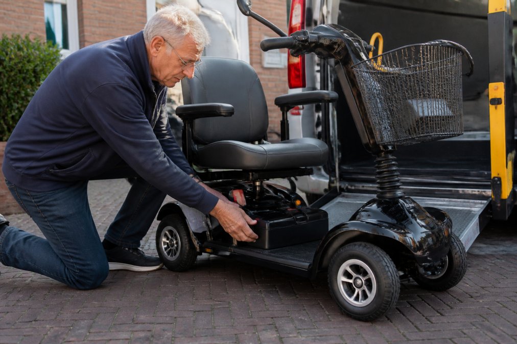 Professioneel voorbereiding van een elektrische scootmobiel voor taxitransport, met focus op de vastzettingspunten, batterijaansluiting en opvouwmechanisme in natuurlijk licht