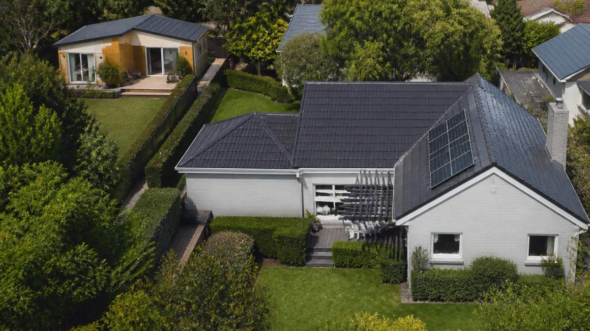 Aerial view of a residential property showing a main house and a smaller secondary dwelling structure in the backyard, separated by mature landscaping and fencing