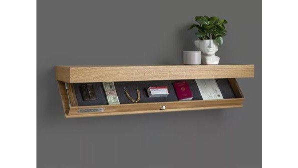 A stylish modern living room with a white Secret Storage Wall Shelf mounted above a console table, a professional woman's hand placing a laptop inside the hidden compartment while the rest of the room stays tidy