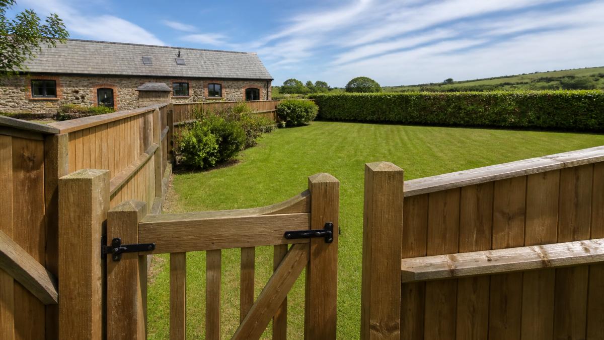 Well-maintained enclosed garden with sturdy timber fencing, secure gate latch, and open lawn space with established hedging, showing quality construction and clear boundaries