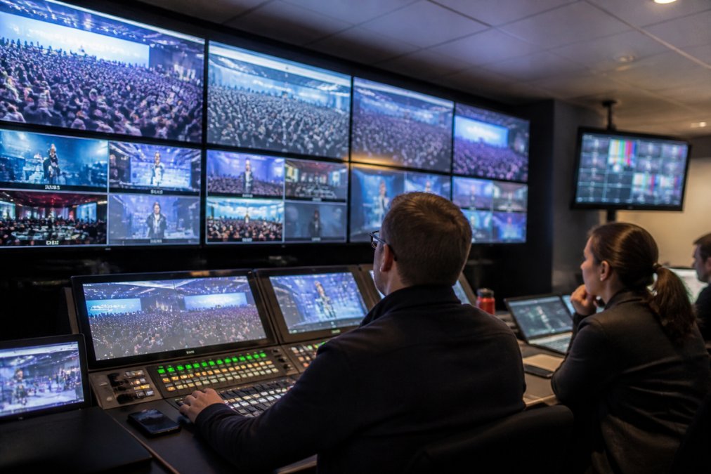 IT security team monitoring live stream broadcast on multiple screens in a control room with network security indicators and real-time metrics visible on displays